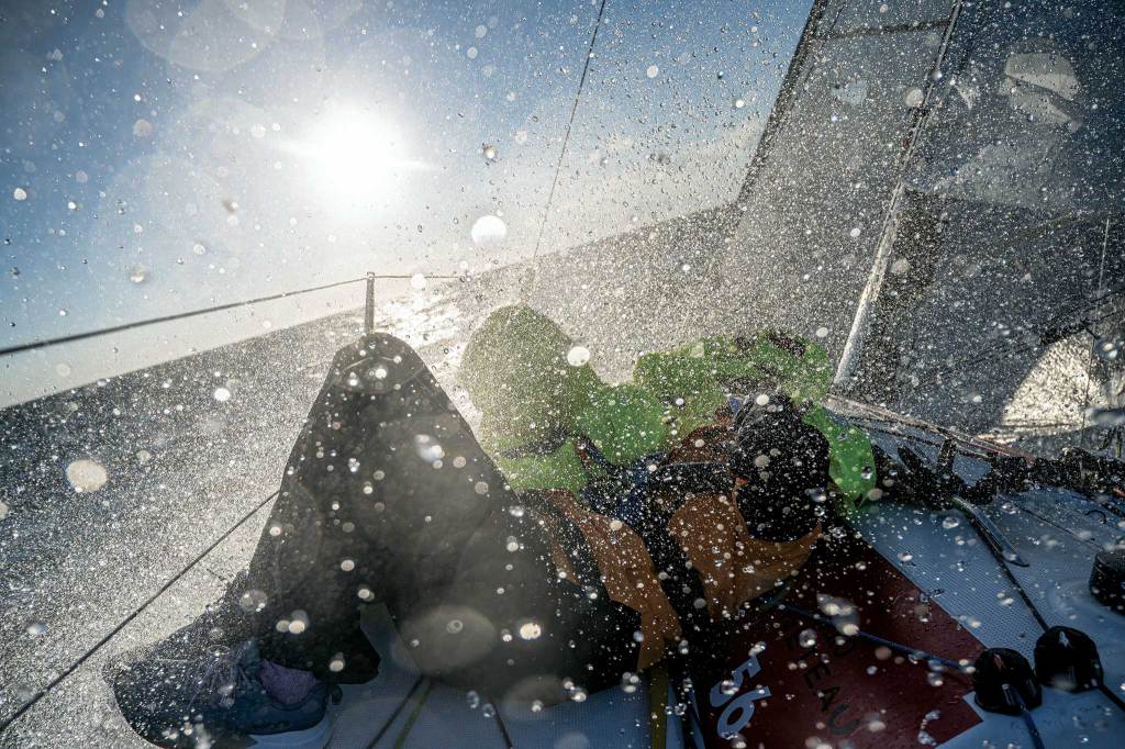 spray into the sunshine with blurred figures on a boat.