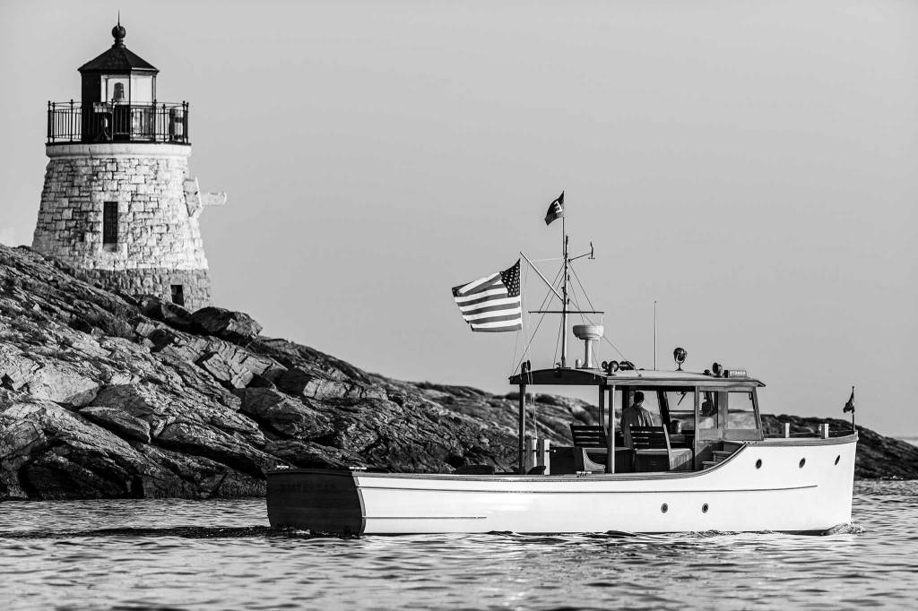 Black and white photograph of a boat in front of a lighthouse