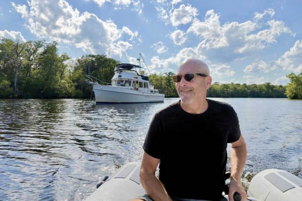 A man in a dinghy with a large boat in the background