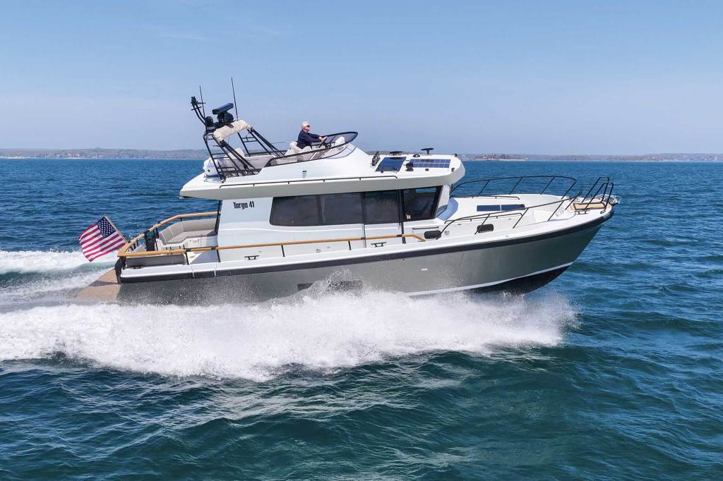 An enclosed motorboat cruising through the water in profile.