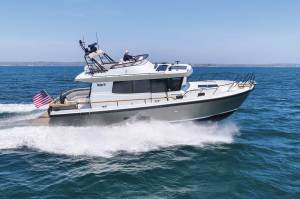 An enclosed motorboat cruising through the water in profile.