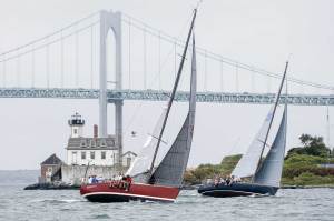 Two boats sailing with a bridge in the distance.