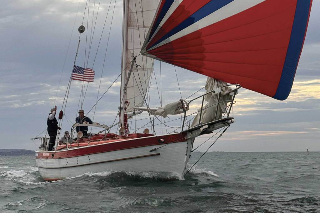 Boat sailing along with a red, white & blue spinnaker