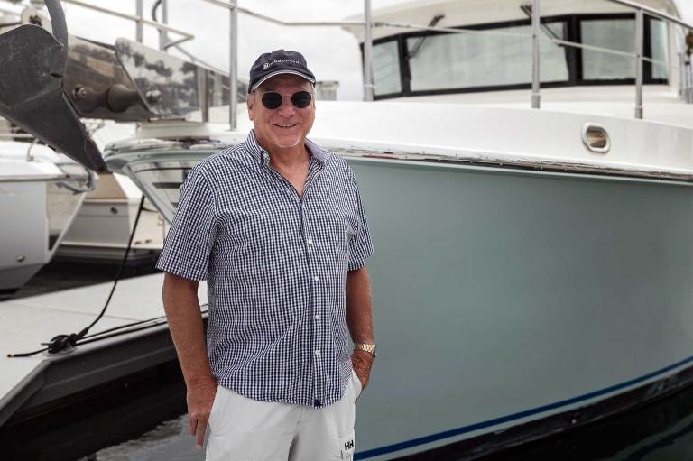 A man smiling (as he should) in front of a boat.